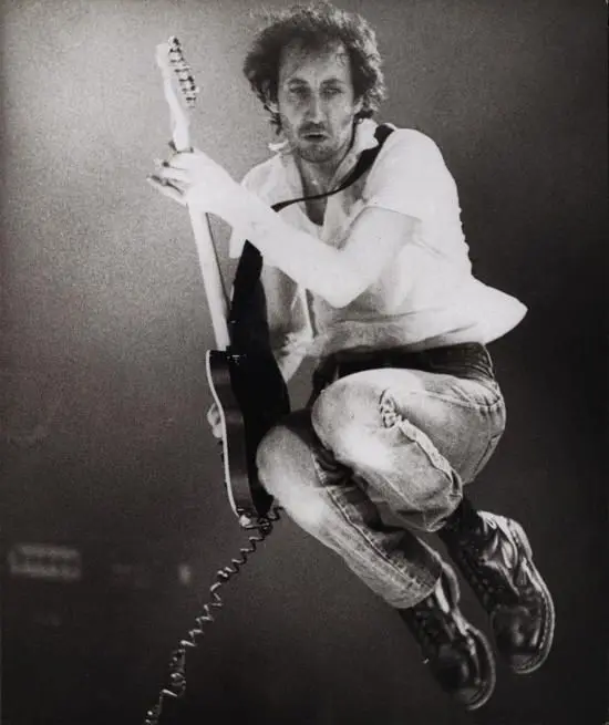 Pete Townshend of The Who mid-leap with his guitar, wearing Dr. Martens boots