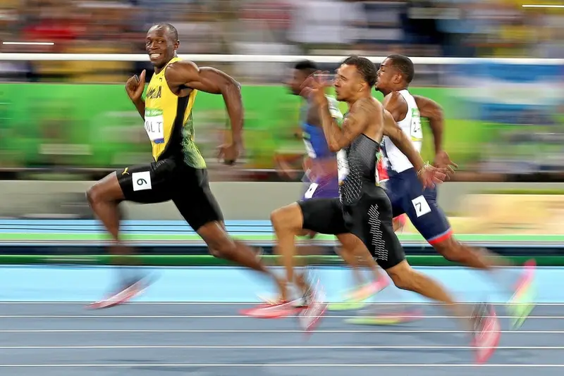 Usain Bolt glancing back with a grin as he leads the field in a sprint race