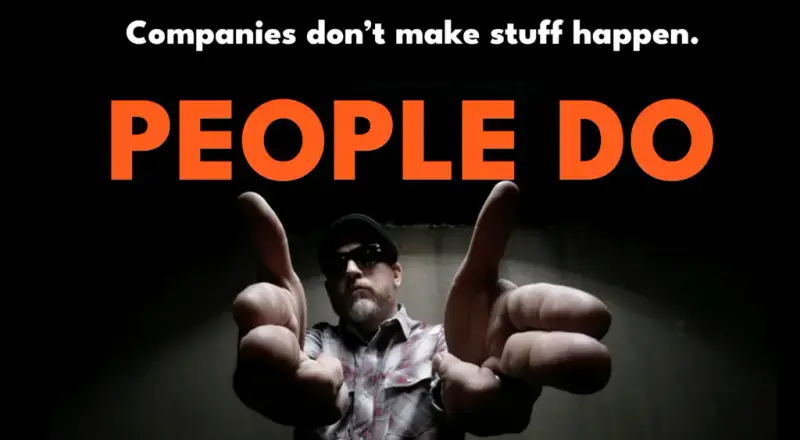 Man in sunglasses pointing at the camera under the words: Companies don't make stuff happen. PEOPLE DO