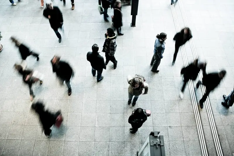 Overhead view of commuters hurrying across a station concourse, most blurred by motion
